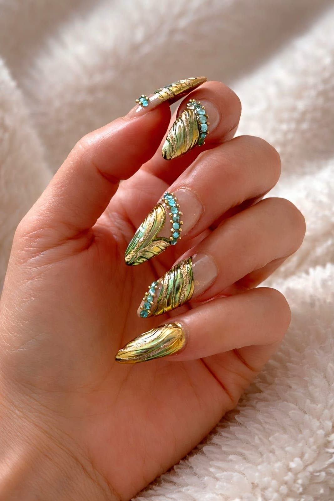 Gold chrome almond nails with stone accents
