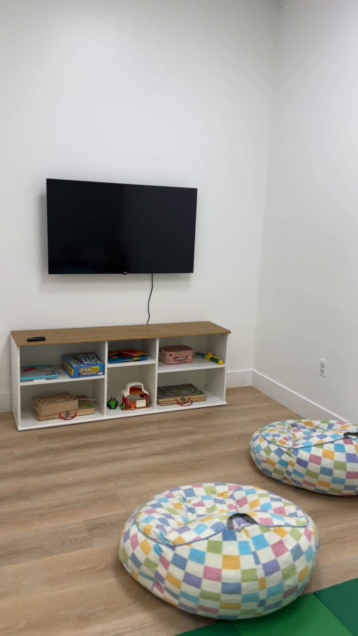 The kids room with a TV, toy shelves and bean bags